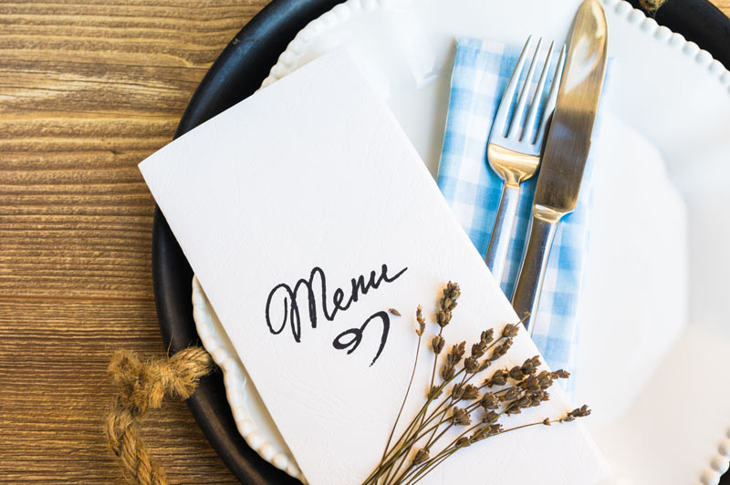image that shows a nicely designed menu on top of the dish and cutlery at a restaurant